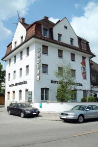 deux voitures garées devant un bâtiment blanc dans l'établissement Hotel Moosbichl, à Munich