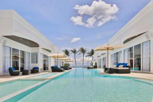 a pool at a resort with chairs and umbrellas at The Privilege Hotel Ezra Beach Club in Bangrak Beach