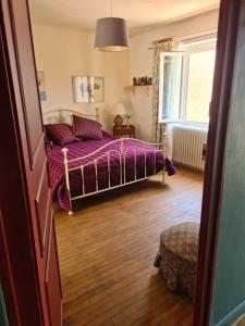 a bedroom with a bed with purple sheets and a window at Le Jardin Secret in Monflanquin