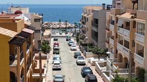 a city street with parked cars and the ocean at Kustdroom in Villaricos