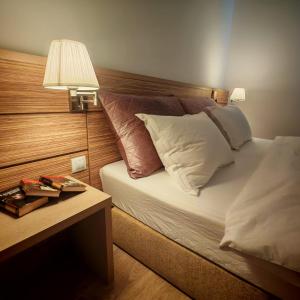 a bed with pillows and a table with a lamp at My-RIN in Otopeni