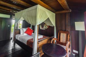 a bedroom with a canopy bed and a table at Balam Bali Villa in Mengwi +92 photos