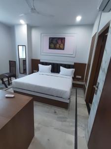 a bedroom with a white bed and a table at Hotel Roshanee in Jaipur