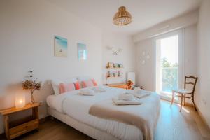 a white bedroom with a large bed with towels on it at PanoramiK Hippodrome - 2 ch - Parking - By Primo concIergerie in Caen