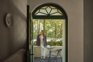 eine Frau, die auf einer Veranda steht und aus einer Tür schaut in der Unterkunft Willa Deco Sopot by Downtown Apartments in Sopot