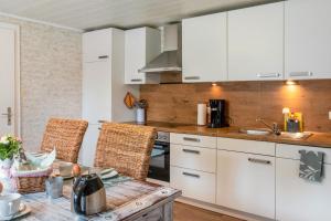 a kitchen with white cabinets and a table with chairs at Dat Jollenhuus in Ihlow