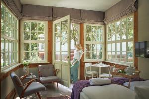 Eine Frau steht in einem Zimmer mit Fenstern in der Unterkunft Willa Deco Sopot by Downtown Apartments in Sopot