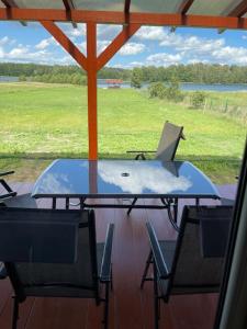 a table and chairs on a porch with a view of a field at Ostoja Spokoju in Czarnówka