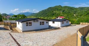 a small white house with a fence and mountains in the background at Stone Village Transfagarasan in Oeștii Ungureni