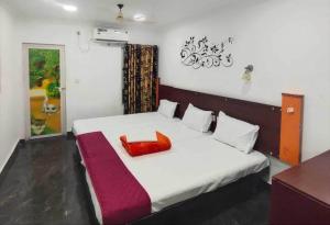 ein Schlafzimmer mit einem weißen Bett mit einem roten Kissen in der Unterkunft SPOT ON Mughal Beach Resort in Alappuzha