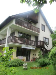 a large white house with a balcony and a yard at Ferienwohnung Troglauer in Letzau