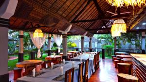 ein Restaurant mit langen Tischen und Stühlen und Kronleuchtern in der Unterkunft Khair Lodge Ambanja in Ambanja