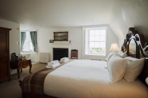 a bedroom with a large white bed and a fireplace at Islay House in Bridgend +25 photos