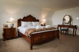 a bedroom with a large bed with a mirror and a table at Islay House in Bridgend