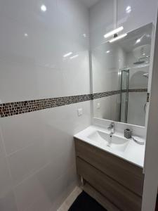 a white bathroom with a sink and a mirror at Le Rouet in Marseille