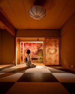 a woman sitting in a room looking out a window at 宿坊 金光院ほたる庵 in Kyoto