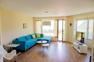 Una sala de estar con un sofá azul y un televisor en Ваканционен апартамент Делфин 14 Holiday Apartment Dolphin 14, en Kavarna