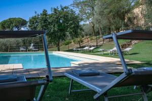 a swimming pool with two lounge chairs next to it at Tuscan Hamlet In Organic Wine Estate in Buonconvento