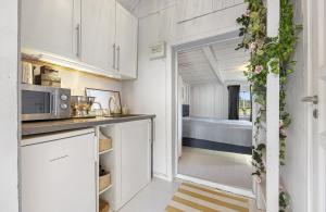 a kitchen with white cabinets and a room with a bed at Lovely Farmhouse By Nidelva With Sauna And Hot Tub in Åmli