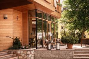 a building with glass doors and chairs on a patio at Corona Dolomites Hotel in Andalo