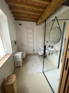 Un baño con lavabo, inodoro y espejo. en 4 Ruderi, en Roccastrada