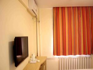 a room with a tv and a window with a radiator at 7 Days Inn Binzhou Zhanhua Fuguo Road in Binzhou