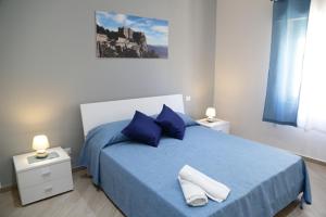 um quarto com uma cama com lençóis azuis e almofadas azuis em La Bussola em Trapani