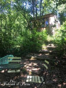 two green chairs and a table in a garden at Chez Federico et Pierre - La cabane en paille in Le Fraysse