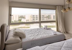 a bedroom with a bed and a large window at شاليه جديد أول استخدام في قلب مارينا ويست خطوات من الممشى in El Alamein
