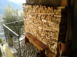 uma pilha de madeira ao lado de um banco ao lado de uma parede em Casa Vacanze Roncaiola em Tirano