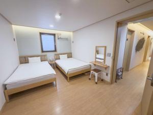 a hospital room with two beds and a mirror at Guest House Brick in Jeju