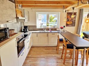 a kitchen with white cabinets and a table with chairs at Ferienhaus Meeresrauschen am Salzhaff - ABC582 in Boiensdorf