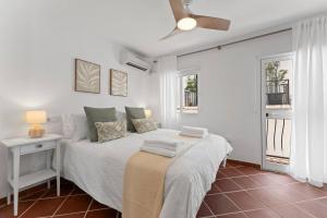 ein weißes Schlafzimmer mit einem Bett mit Nachttisch und zwei Fenstern in der Unterkunft Picturesque Casita Mijas Pueblo in Mijas
