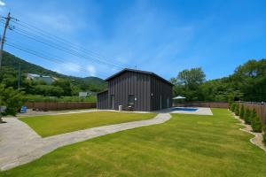 a black building in a yard with a green lawn at Daeboodo Podohyangki Pension in Ansan