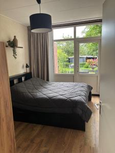 a bedroom with a bed and a large window at De Drentse Rust - Het Atelier in Emmer-Compascuum