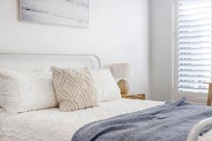 Un dormitorio con una cama con sábanas y almohadas blancas. en Kurrajong, en Rosebud