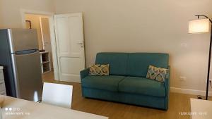 a green couch in a living room with a refrigerator at Nonno 'Drea Guest House in Castiglione della Pescaia