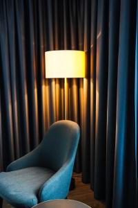 a blue chair and a lamp in front of curtains at Clarion Hotel Air in Sola