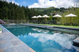 a swimming pool with tables and umbrellas on a resort at Viktan Hotel in Bukovel