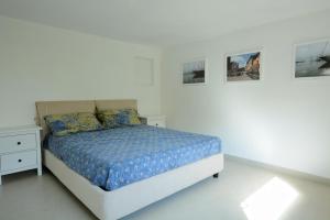 una camera bianca con un letto e immagini appese al muro di Casa Mite a Pietrasanta