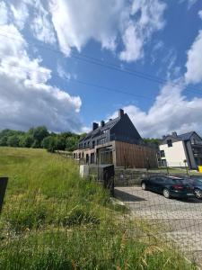 a house with a car parked next to a field at Szczyrkowskie Tarasy in Szczyrk