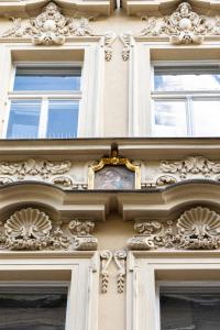 a building with three windows and a clock on it at Six Residences Prague in Prague