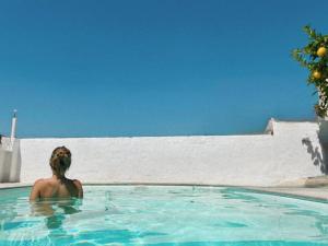 a woman is sitting in a swimming pool at Villa Mediterranea Tossa in Tossa de Mar