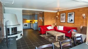 a living room with red couches and a kitchen at Spacious Family Apartment in Hemsedal, Ski In-Out, Sauna, 30m from Skarsnuten hotell in Hemsedal