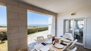 una sala da pranzo con tavolo e vista sull'oceano di Villa Foz ad Aldeia do Meco