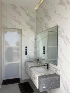Un baño con dos lavabos y un espejo. en شاليه لدن, en Hail