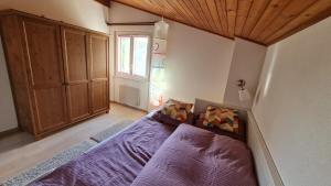 a bedroom with a purple bed and a wooden ceiling at Süße Doppelhaushälfte, mit Garten und Parkplätzen in Bouveret