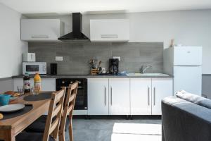 a kitchen with white cabinets and a table with chairs at L'Escapade Mirabeau - Confort à 4 & animaux ok in Hénin-Beaumont