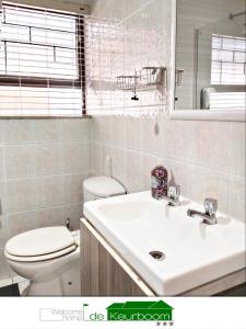 a bathroom with a white sink and a toilet at De Keurboom Guesthouse in Kuilsrivier +106 photos