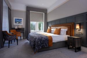 Una habitación de hotel con una cama grande y una silla. en Skeabost House Hotel, en Portree